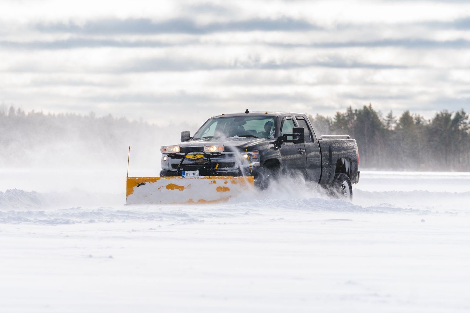Pickup truck with a yellow plow clearing deep snow